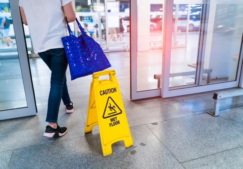 Person Walking Out Of The Building Right Besides Wet Floor Sign